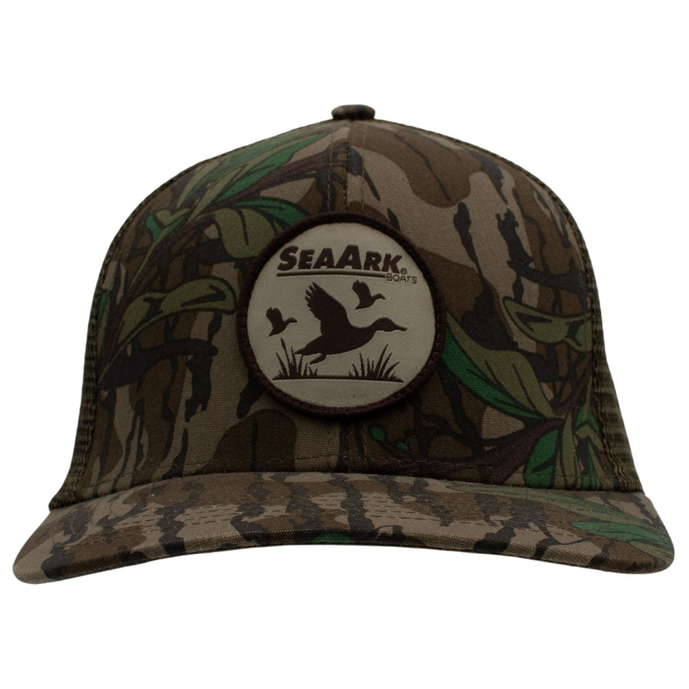 A camouflage trucker hat with a circular SeaArk patch on the front, featuring a brown and green woodland camo pattern with a central duck silhouette.