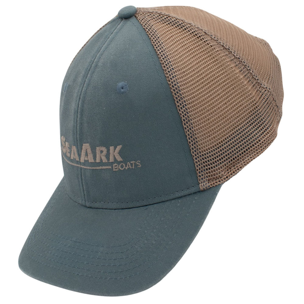 Side of a trucker-style baseball cap with a blue-grey front panel and brim, tan mesh back panels, and a small embroidered logo on the front.